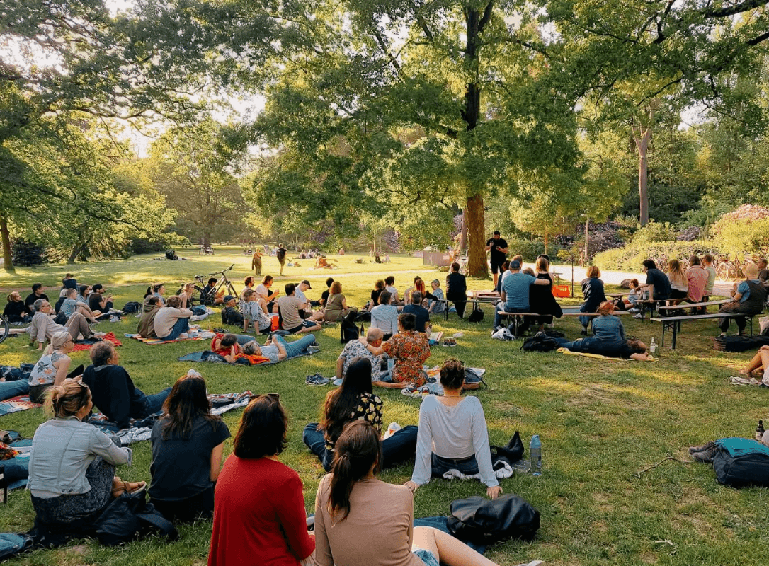 Menschen sitzen im Grünen und lauschen einer Lesung