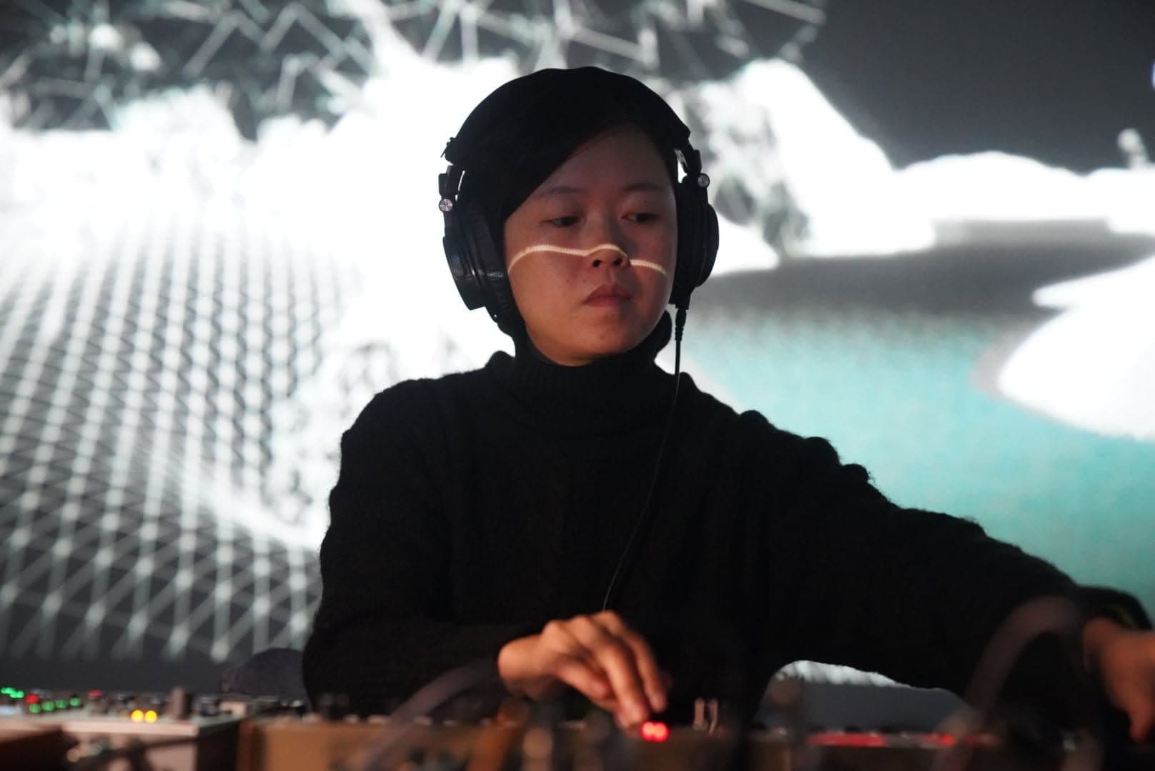 Die Musikerin Wu Zhuoling steht mit Kopfhörern an einem Mischpult