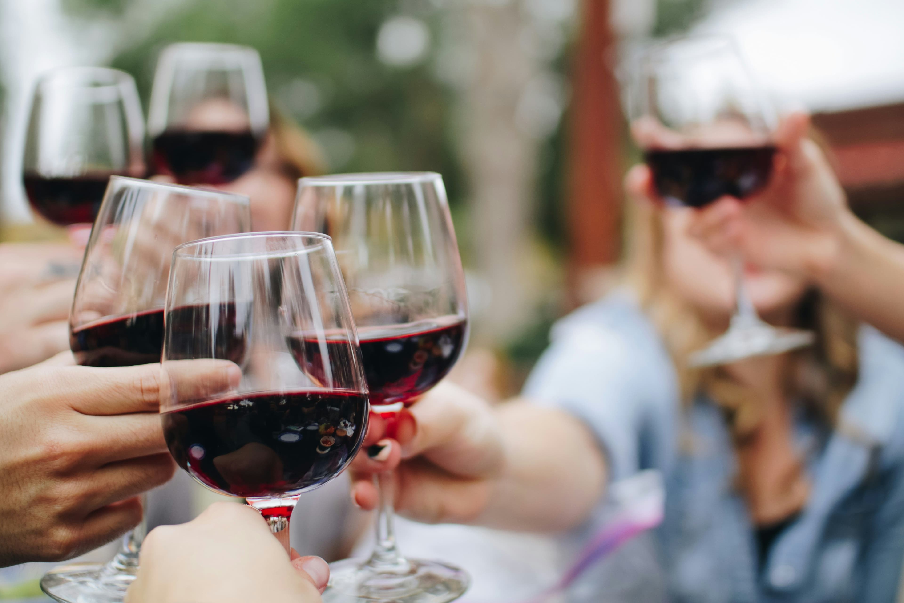 Weingläser mit Rotwein werden angestoßen