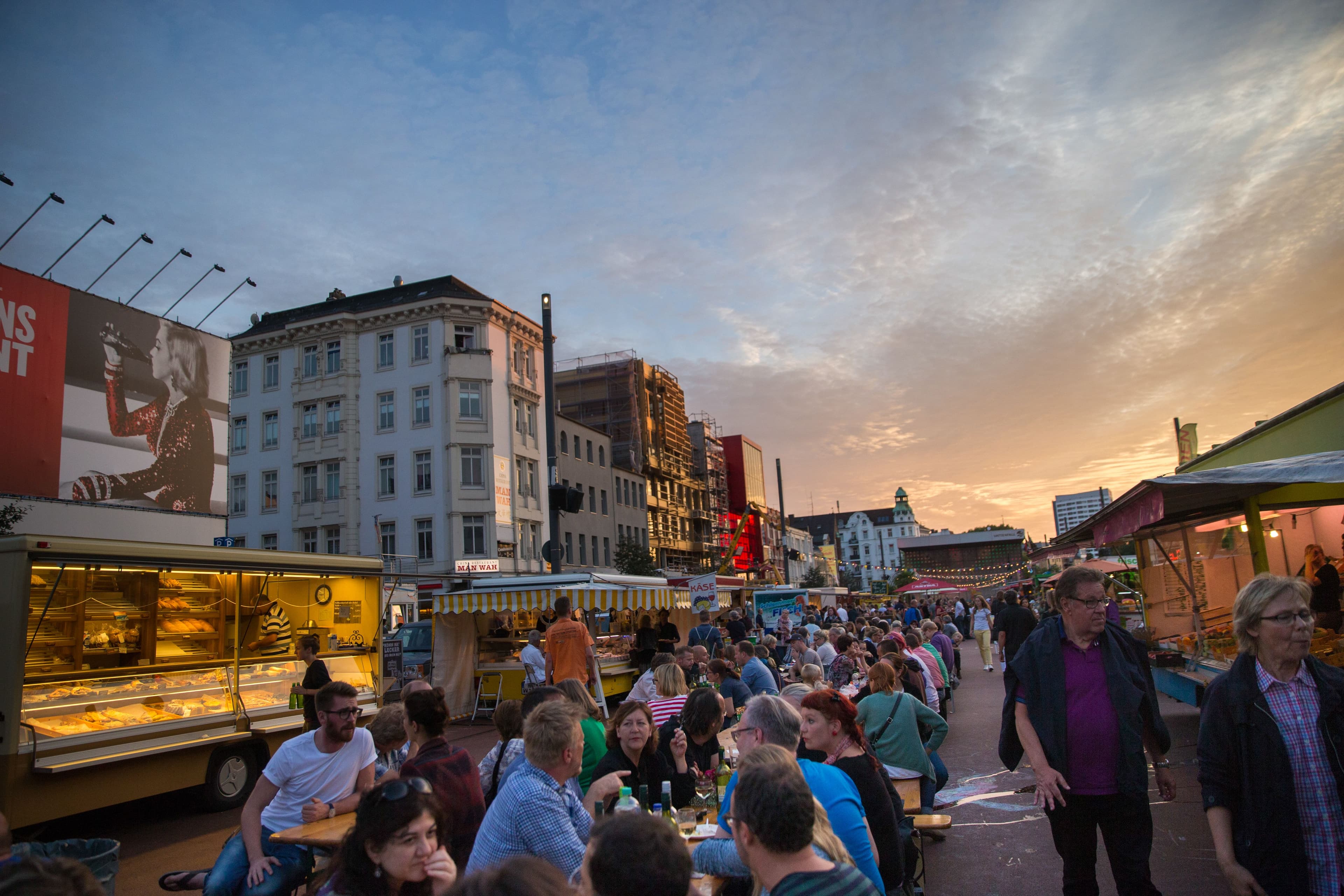 Menschen sitzen auf dem St. Pauli Nachtmarkt zwischen Ständen