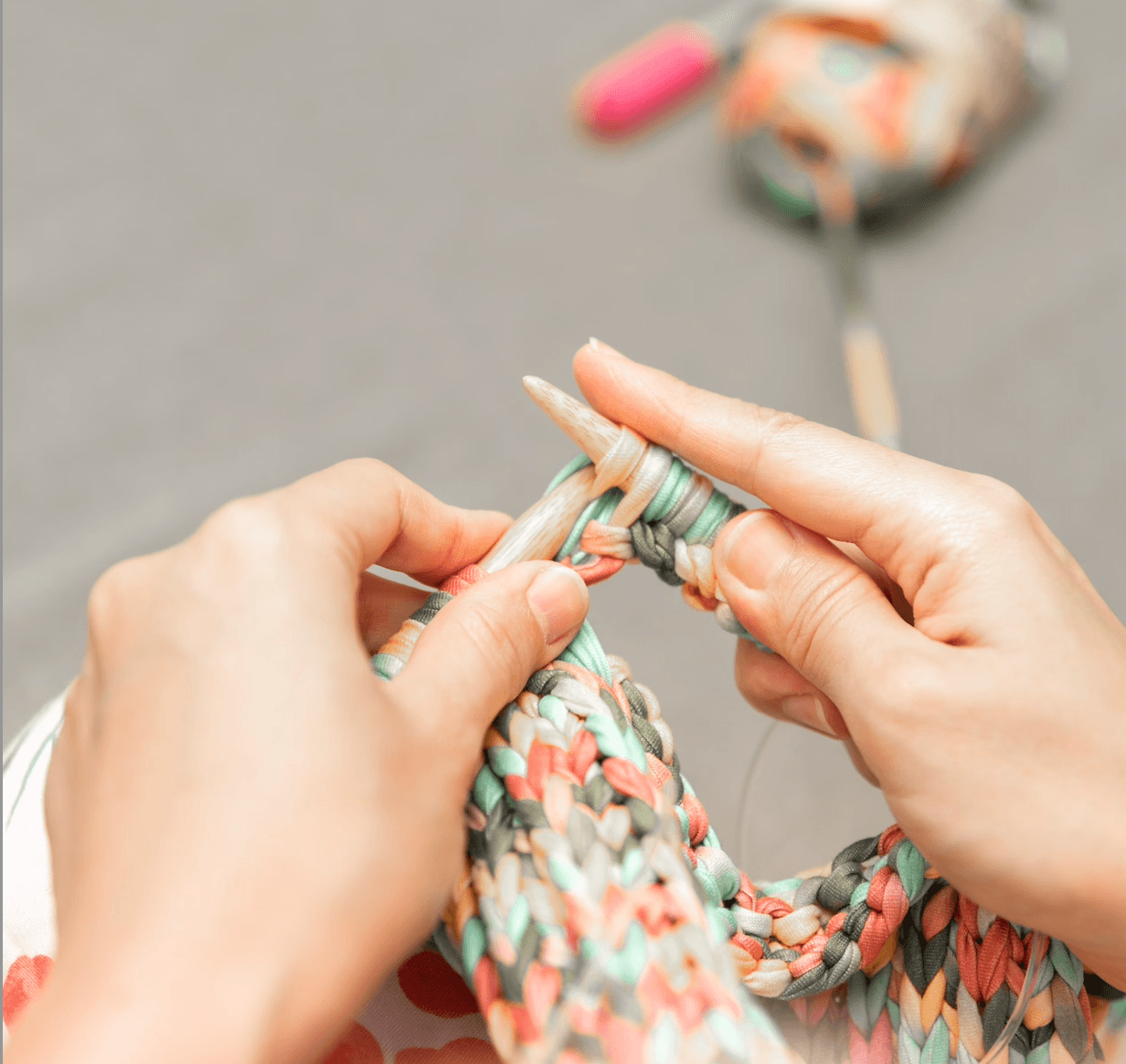 Zwei Hände stricken ein Kleidungsstück
