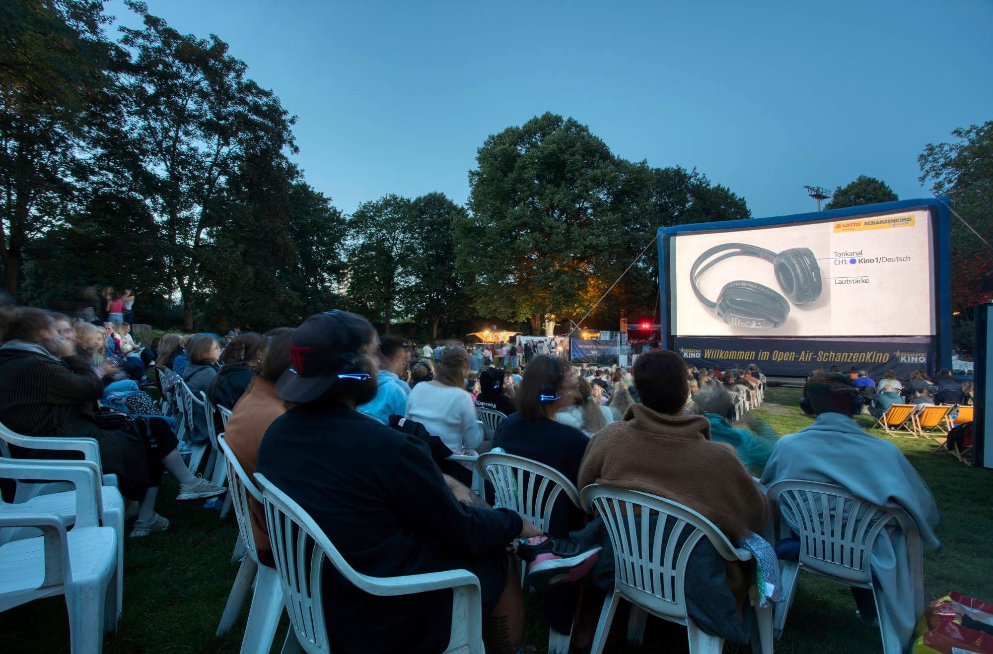Personen beim Open-Air-Schanzen Kino auf Plastikstühlen