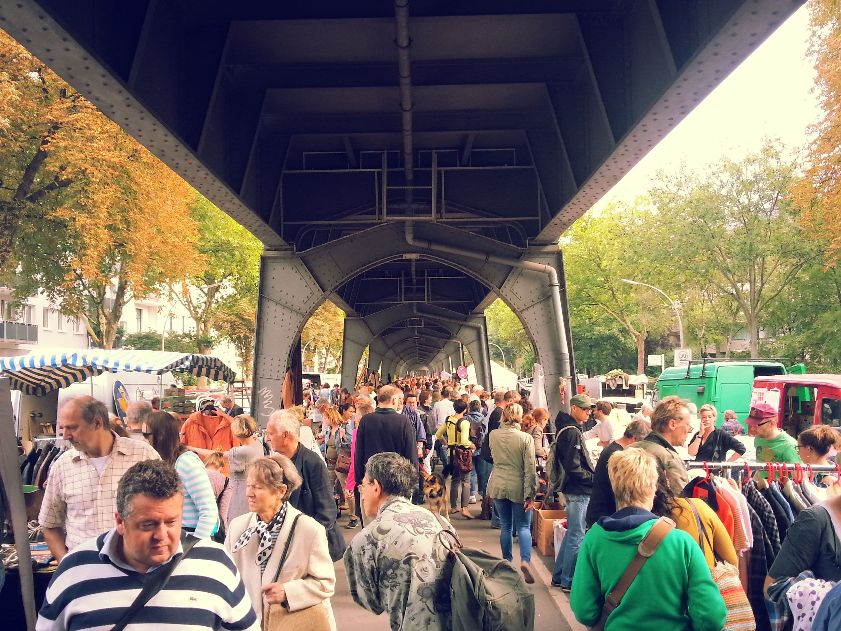 Menschen schlendern unter der Hochbahnbrücke durch die Isestraße.