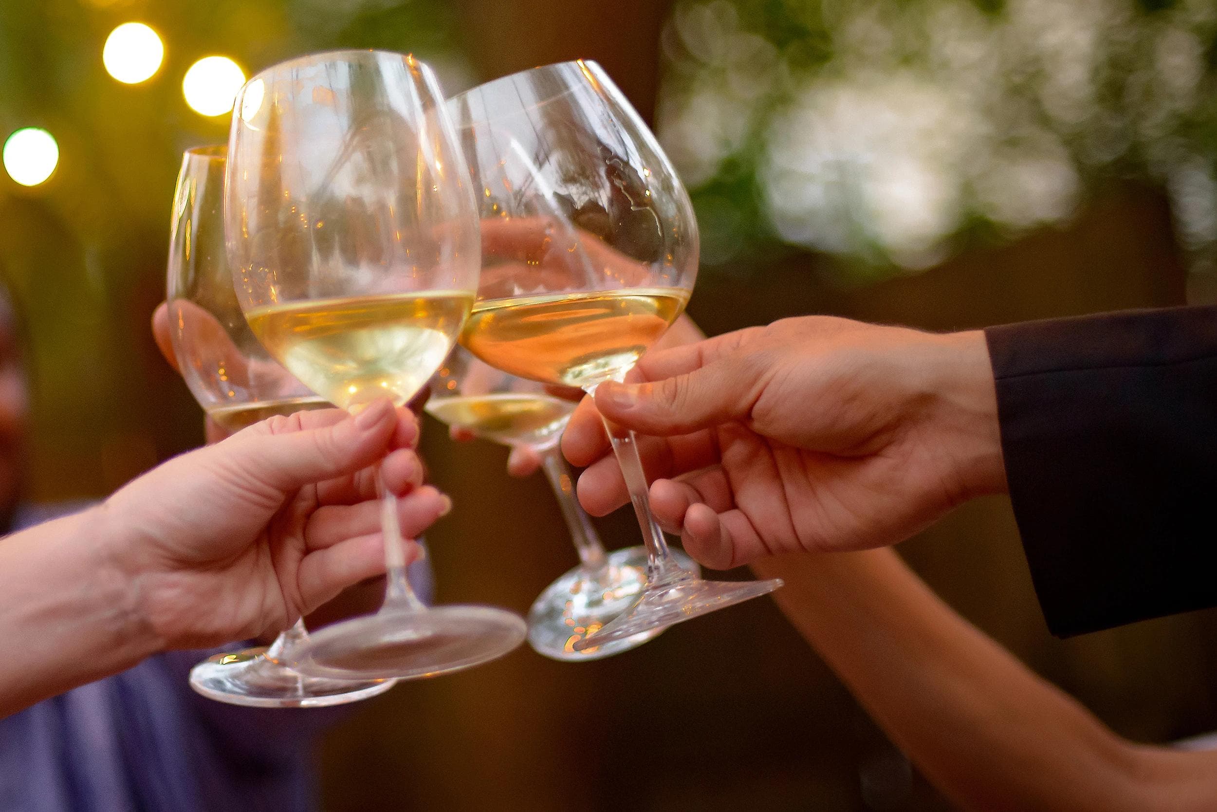 Leute stoßen mit Weißwein an