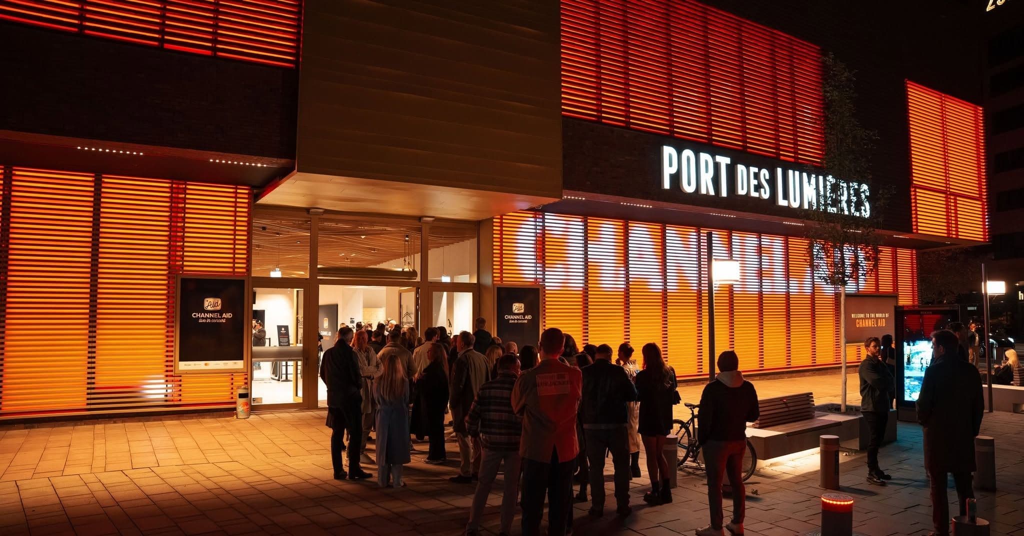 Menschen stehen in einer Schlange vor dem Eingang des Port des Lumières