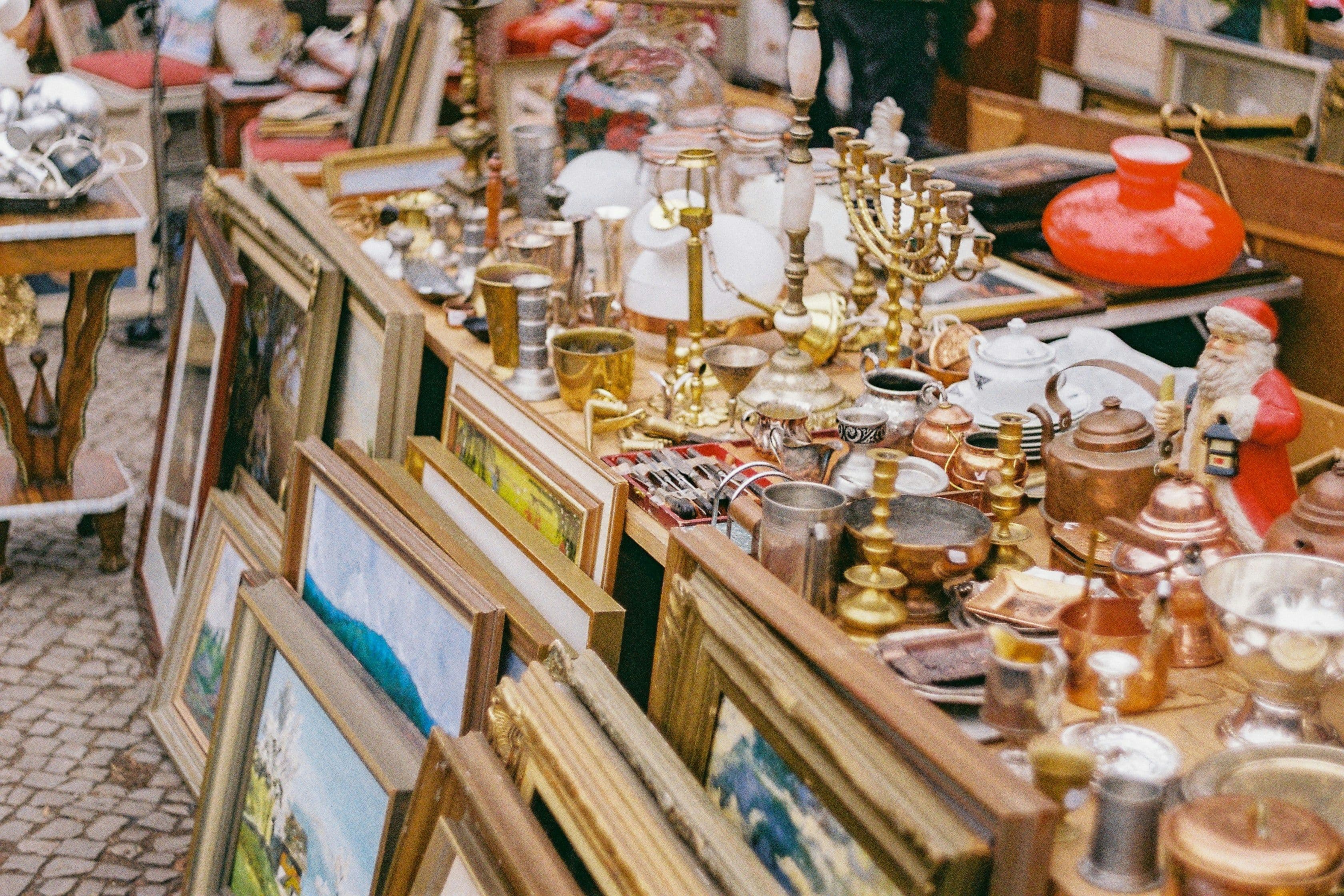 Bilderrahmen und Trödel stehen an und auf einem Flohmarktstand
