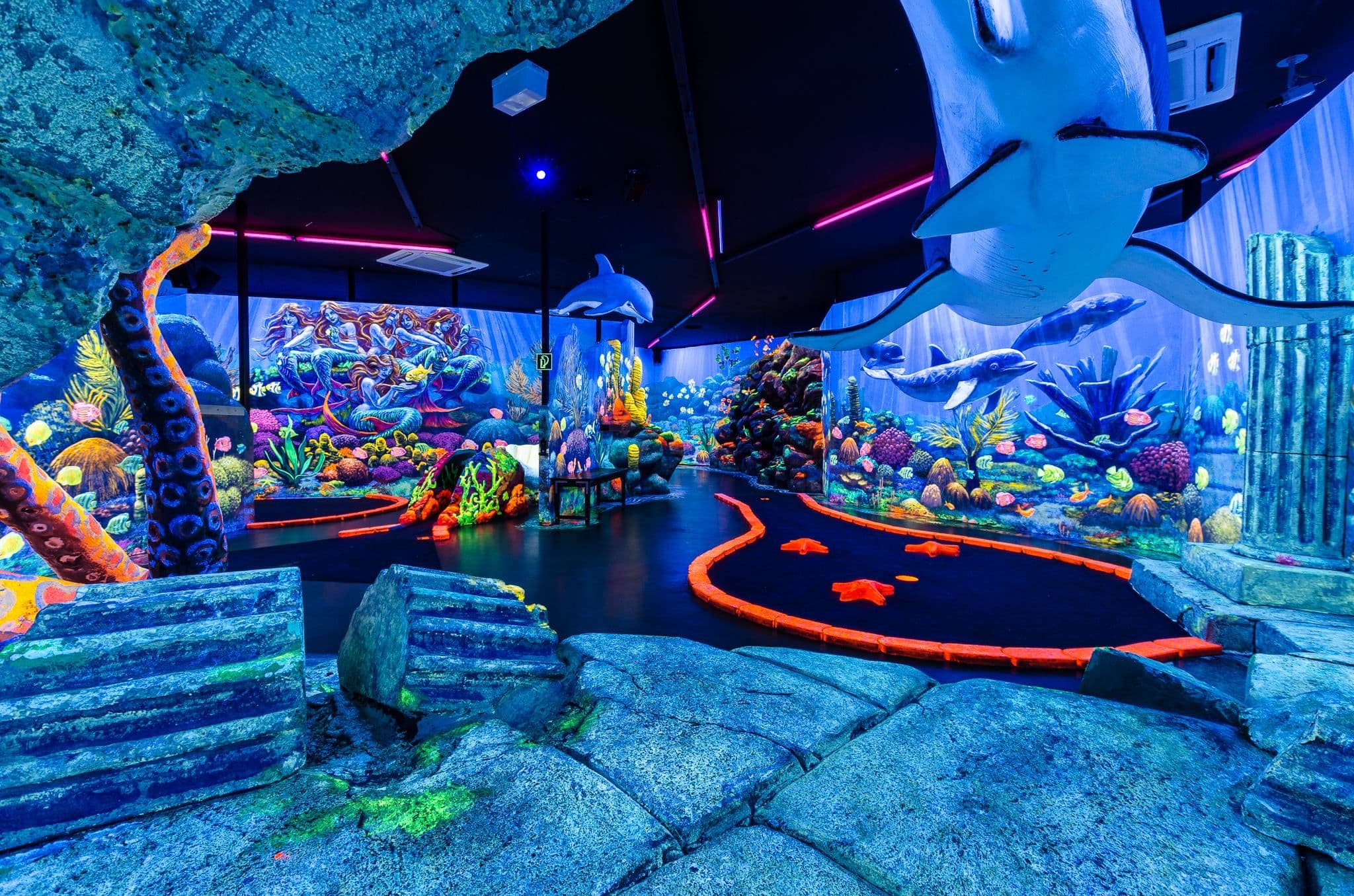 Eine in neonfarben beleuchtete Minigolfbahn