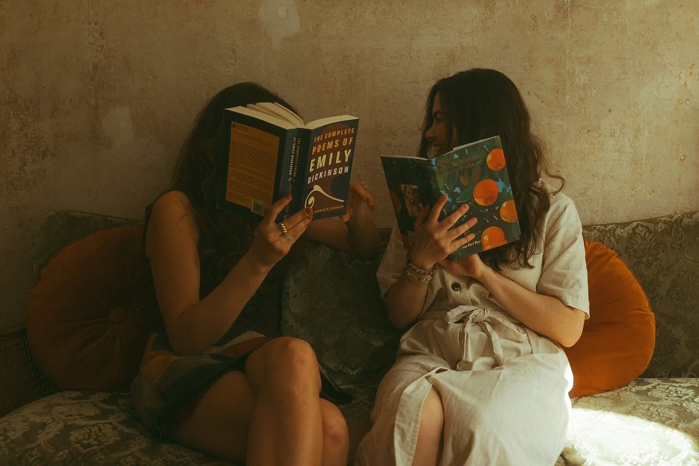 Zwei Autor:innen halten sich Bücher vor ihre Gesichter