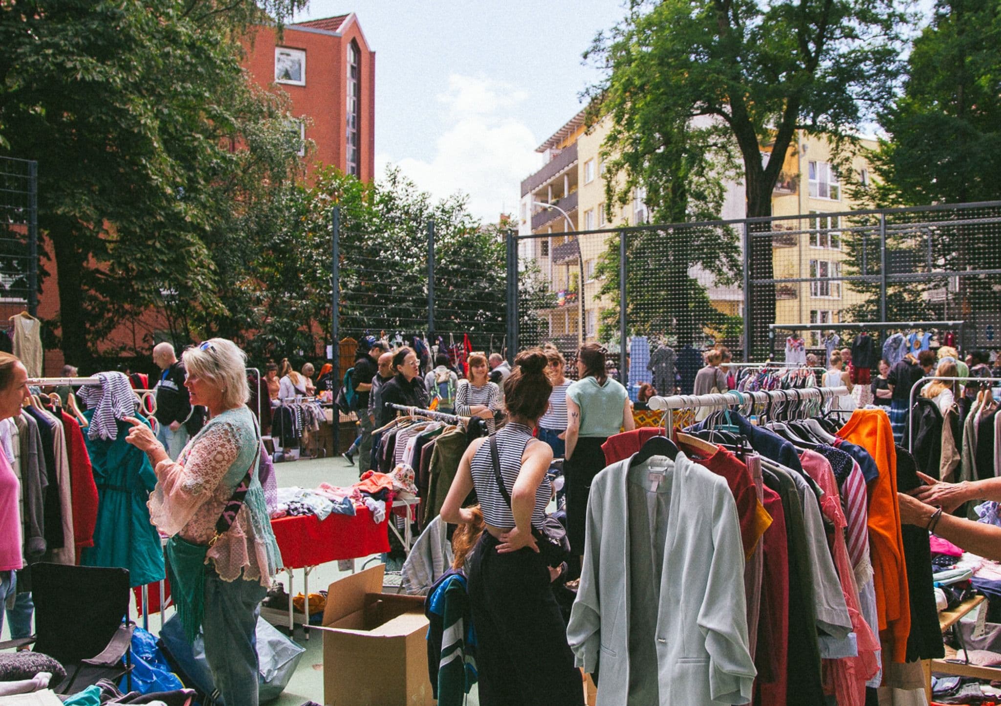 Personen bei Kleiderstangen auf einem Flohmarkt