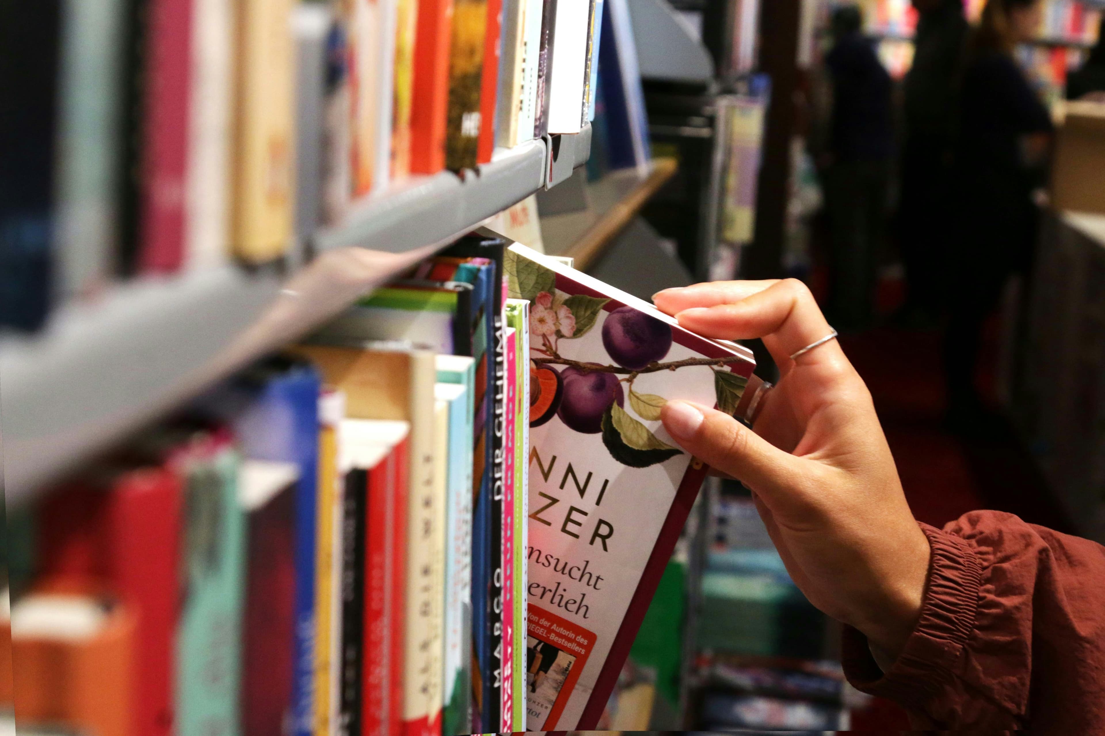 Eine Hand nimmt ein Buch aus einem Bücherregal