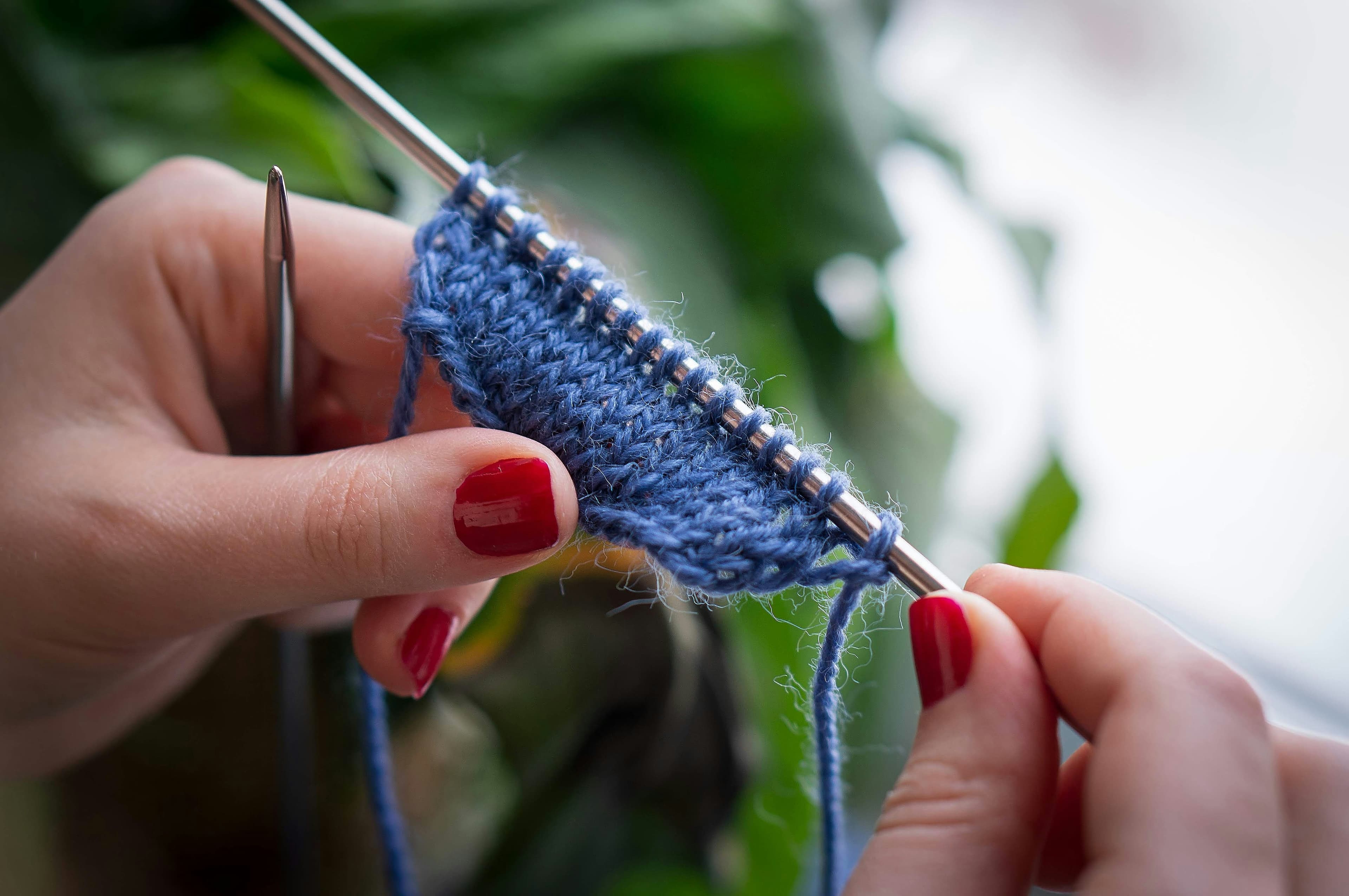 Eine Frau mit Wolle und Stricknadeln