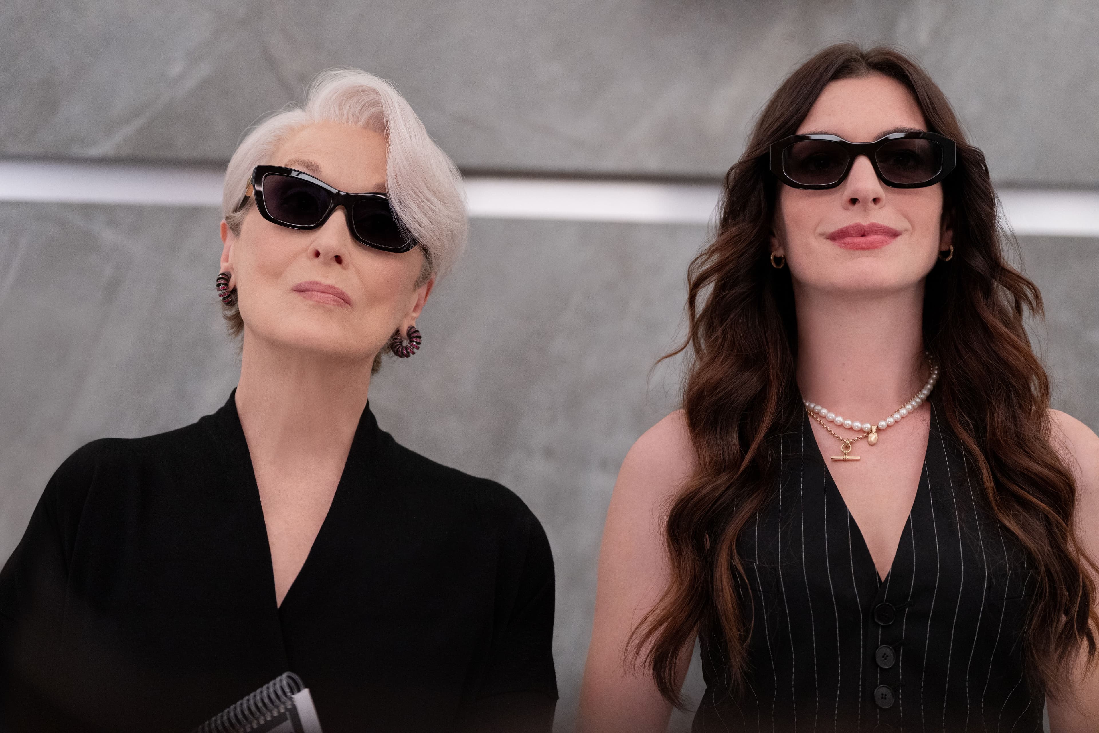 Meryl Streep und Anne Hathaway tragen beide Sonnenbrillen und stehen nebeneinander