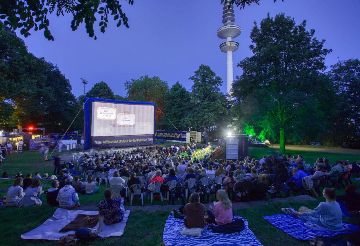 Personen beim Open-Air-Schanzen Kino auf Decken und Plastikstühlen