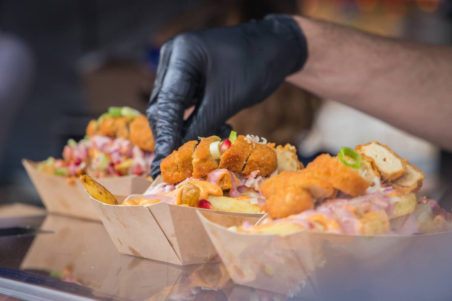 Hand mit Handschuh bereitet Essen zu