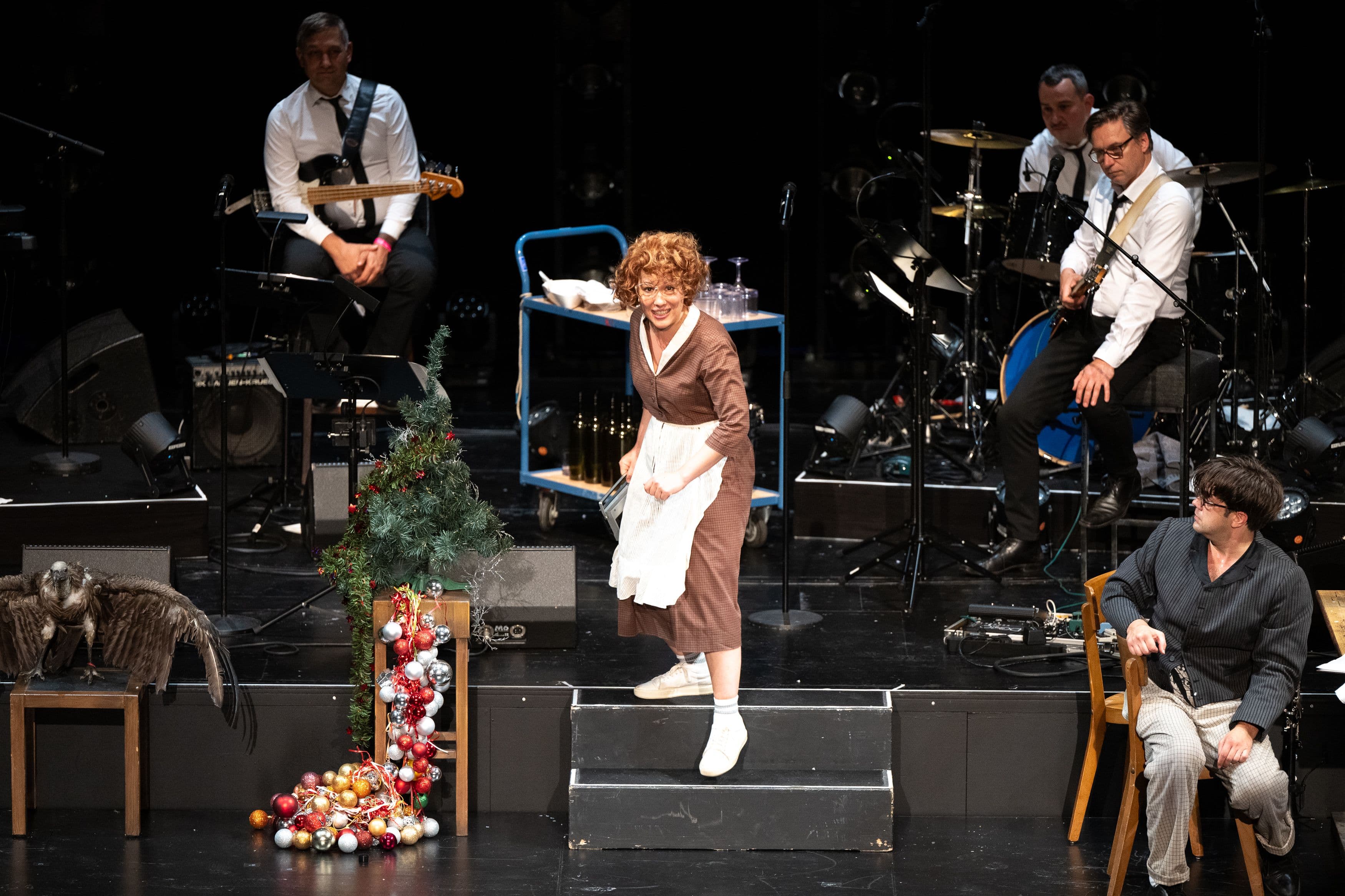 Eine Frau und mehrere Männer spielen auf einer Theaterbühne
